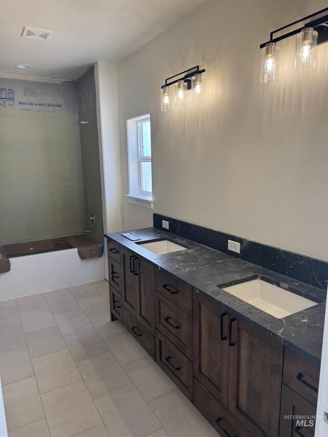 bathroom with tile patterned flooring, a tub to relax in, and vanity