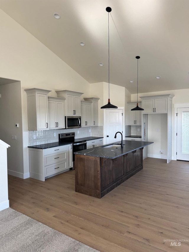 kitchen with decorative backsplash, a kitchen island with sink, stainless steel appliances, and a sink