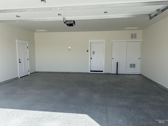 garage with a garage door opener, visible vents, and baseboards