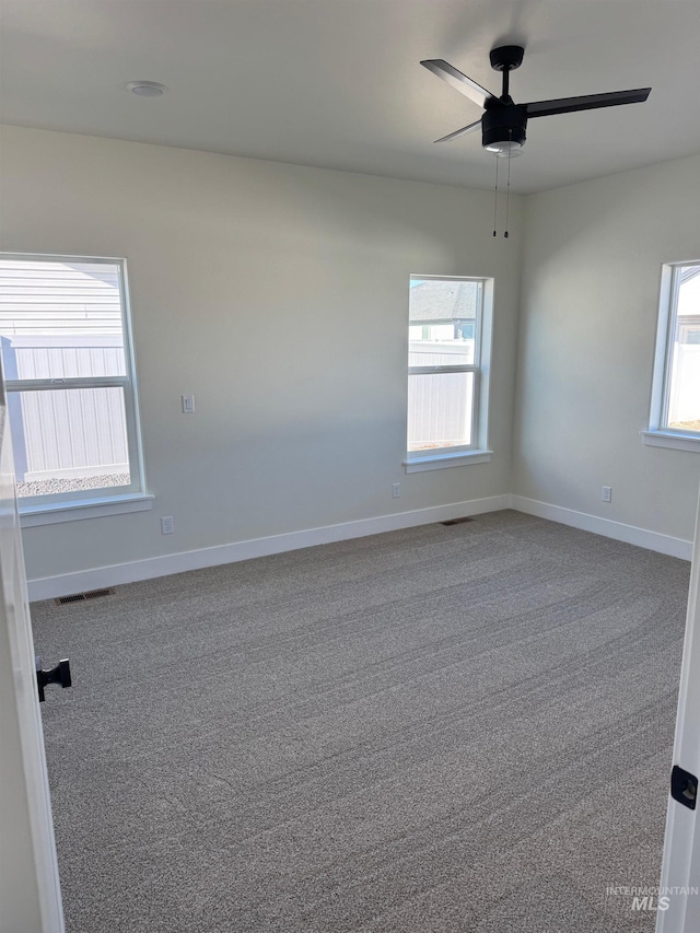 carpeted spare room with baseboards, a ceiling fan, and visible vents