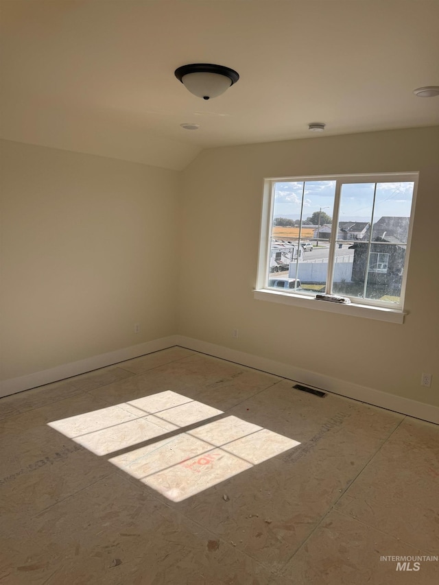 empty room featuring vaulted ceiling and light tile patterned floors