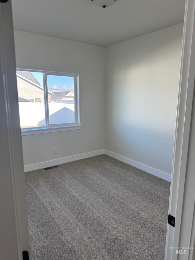 carpeted spare room with visible vents and baseboards