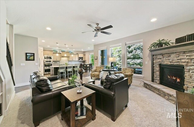 448 E Eaglewoods Ln, Eagle, ID 83616 - living area featuring a stone fireplace, recessed lighting, ceiling fan, baseboards, and light carpet