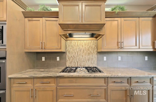 448 E Eaglewoods Ln, Eagle, ID 83616 - kitchen with decorative backsplash, stainless steel appliances, exhaust hood, and light stone counters