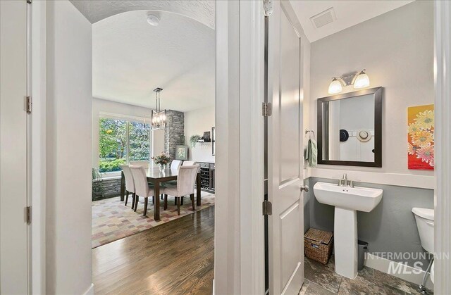 448 E Eaglewoods Ln, Eagle, ID 83616 - half bath with toilet, wood finished floors, a chandelier, baseboards, and a sink