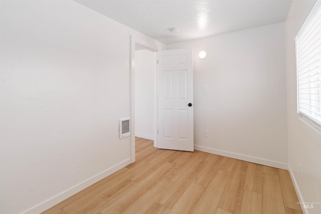 spare room featuring light wood-style floors, visible vents, and baseboards