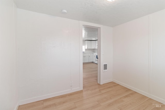 spare room with visible vents, baseboards, and light wood finished floors