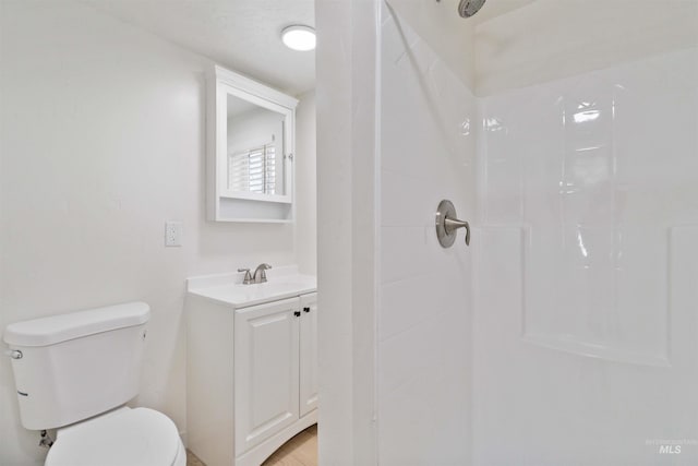 bathroom featuring toilet, a shower, and vanity