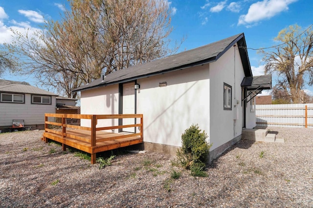 exterior space featuring fence, a wooden deck, and stucco siding