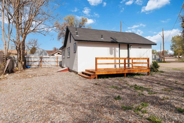 rear view of property featuring fence and stucco siding
