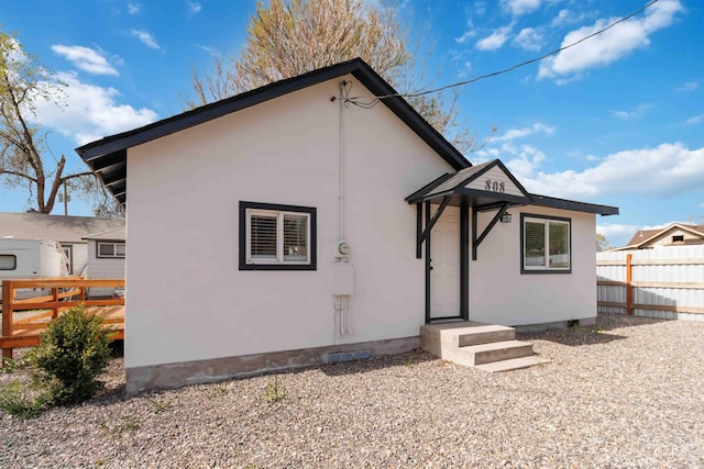 back of property featuring stucco siding and fence