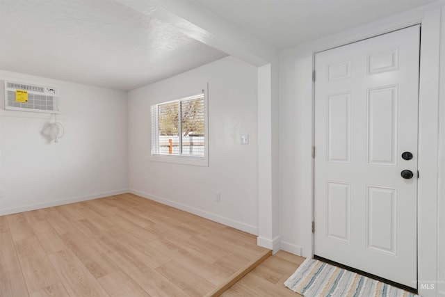 entrance foyer with a wall unit AC, light wood finished floors, and baseboards