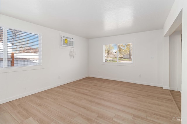 unfurnished room featuring light wood-type flooring, plenty of natural light, and a wall unit AC