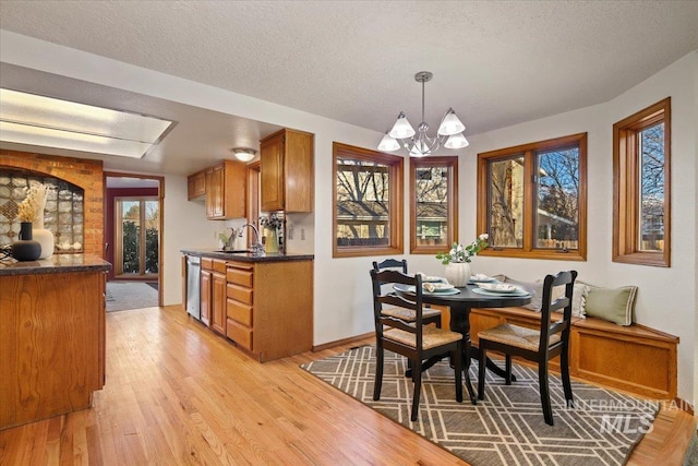 dining space with sink, an inviting chandelier, plenty of natural light, light hardwood / wood-style floors, and a textured ceiling