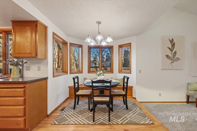 dining area featuring light hardwood / wood-style flooring, a textured ceiling, and a chandelier