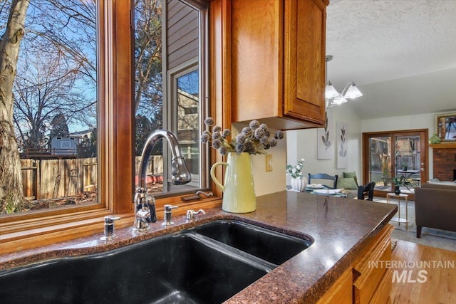 kitchen featuring sink, pendant lighting, a textured ceiling, and an inviting chandelier