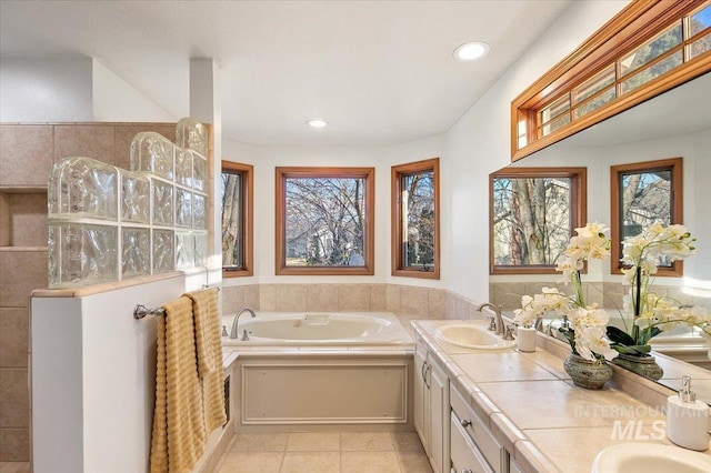 bathroom featuring tile patterned floors, a bathing tub, a wealth of natural light, and vanity