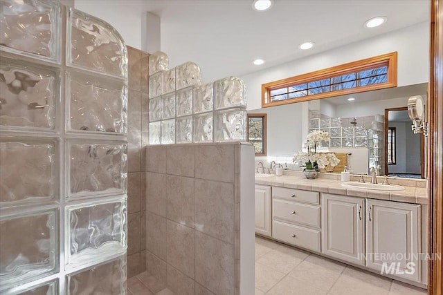 bathroom with tile patterned floors, vanity, and tiled shower