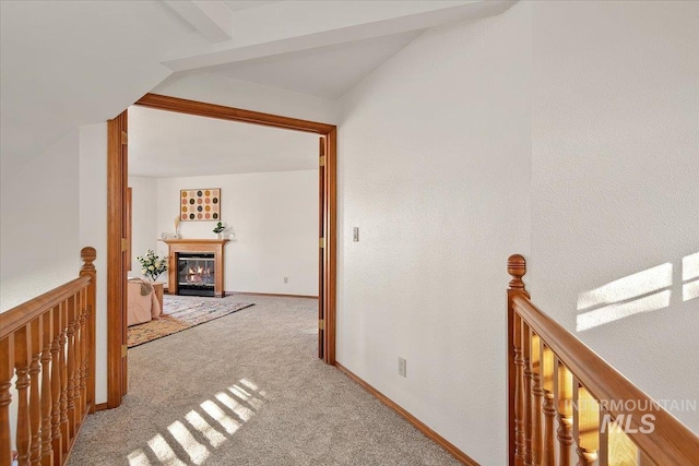 hallway featuring beam ceiling and light colored carpet