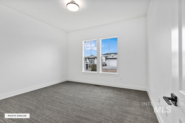 empty room with visible vents, baseboards, and dark colored carpet