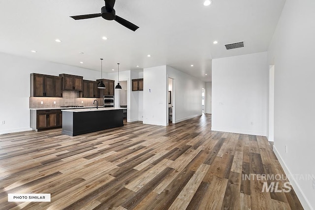 kitchen featuring visible vents, a sink, open floor plan, ceiling fan, and wood finished floors