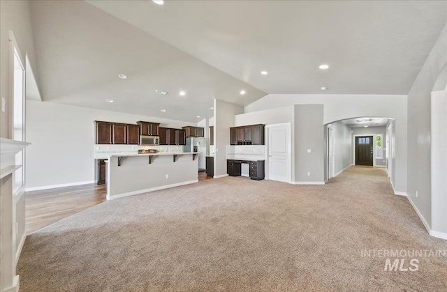 3225 N Quarrystone Way, Meridian, ID 83646 - unfurnished living room featuring light colored carpet, arched walkways, high vaulted ceiling, baseboards, and recessed lighting