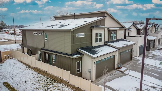 941 E Bissett St, Meridian, ID 83642 - snow covered property with driveway, a residential view, an attached garage, fence, and board and batten siding
