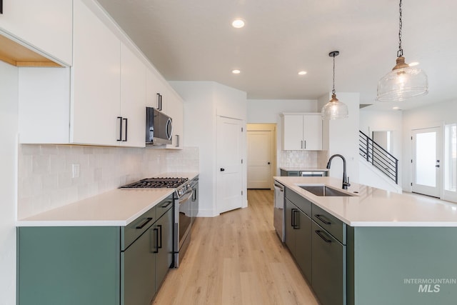 kitchen with appliances with stainless steel finishes, white cabinets, a sink, and light countertops