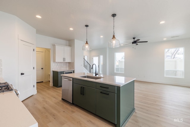 kitchen with a center island with sink, range, light countertops, stainless steel dishwasher, and a sink