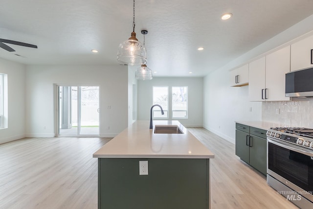 kitchen with tasteful backsplash, open floor plan, light countertops, stainless steel appliances, and a sink