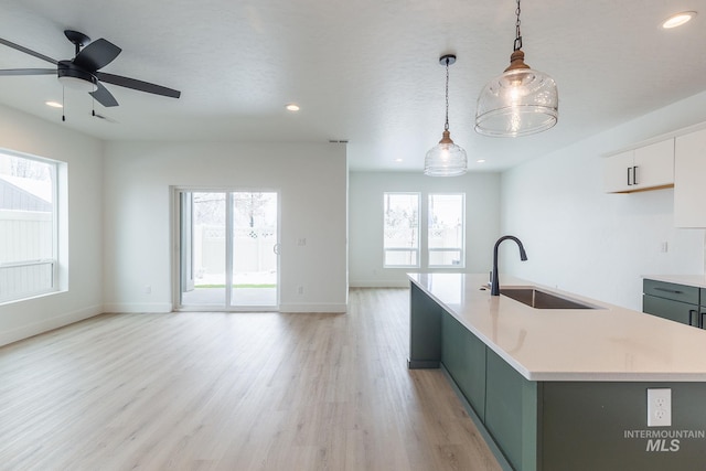 kitchen with light wood-type flooring, light countertops, a sink, and open floor plan