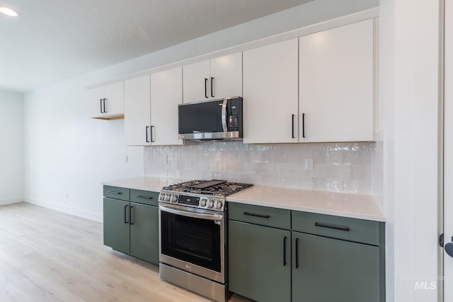 kitchen featuring baseboards, light wood-style floors, light countertops, appliances with stainless steel finishes, and decorative backsplash