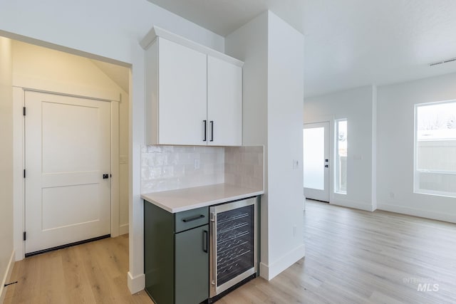 kitchen featuring wine cooler, visible vents, light countertops, light wood-type flooring, and decorative backsplash