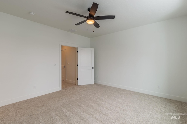 spare room with a ceiling fan, visible vents, light carpet, and baseboards