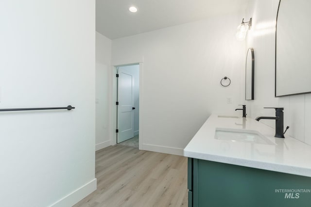 bathroom featuring baseboards, a sink, and wood finished floors