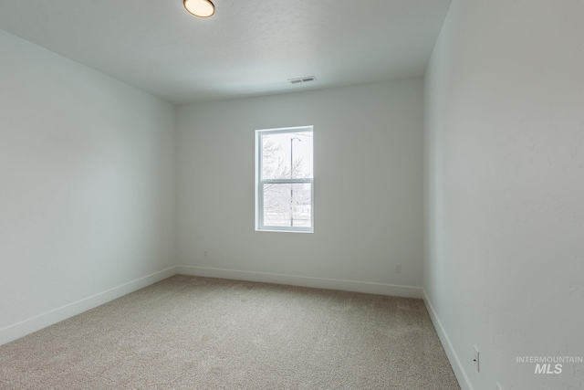 empty room featuring visible vents, light carpet, and baseboards