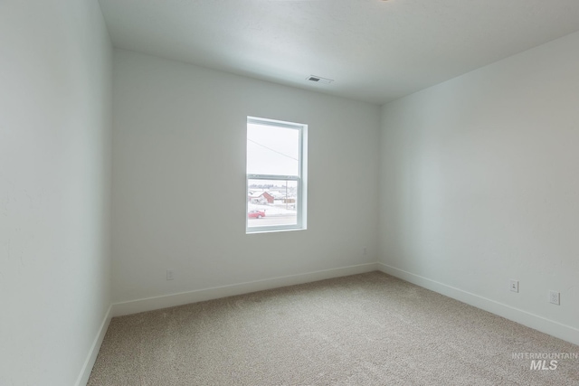 empty room with carpet, visible vents, and baseboards