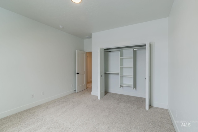 unfurnished bedroom with a closet, baseboards, and carpet flooring