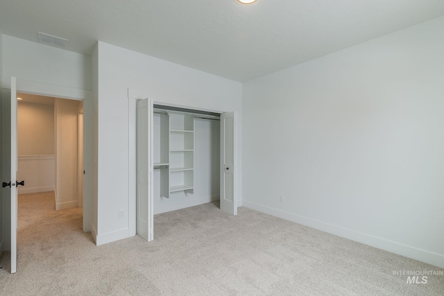 unfurnished bedroom featuring visible vents, baseboards, a closet, and light colored carpet