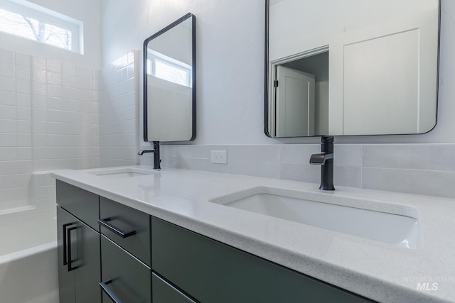 bathroom with double vanity, a sink, and a healthy amount of sunlight