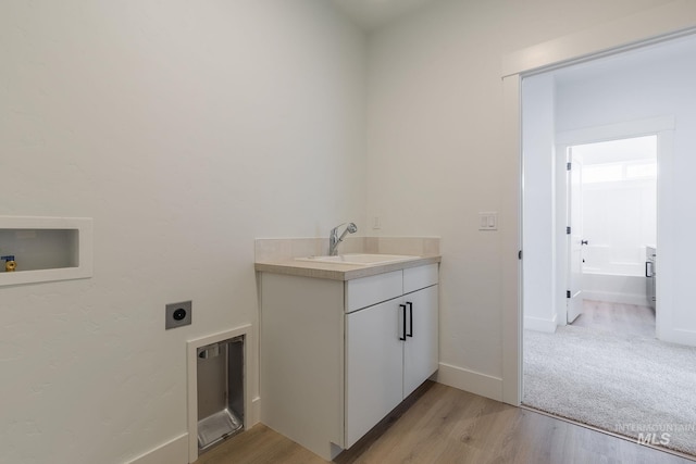 laundry area with washer hookup, light wood finished floors, a sink, electric dryer hookup, and baseboards