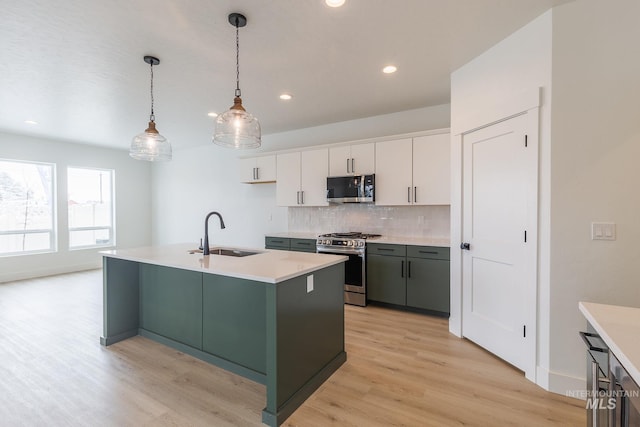 kitchen with stainless steel appliances, light countertops, backsplash, white cabinets, and a sink