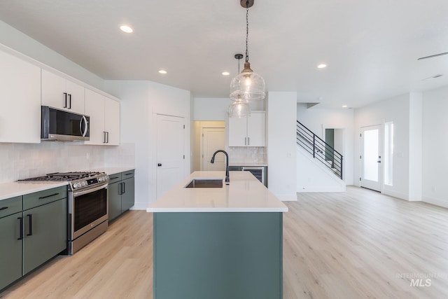 kitchen with decorative light fixtures, light countertops, light wood-style floors, a sink, and gas range