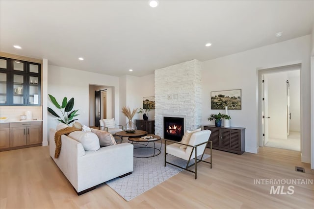 living room featuring light hardwood / wood-style floors and a stone fireplace