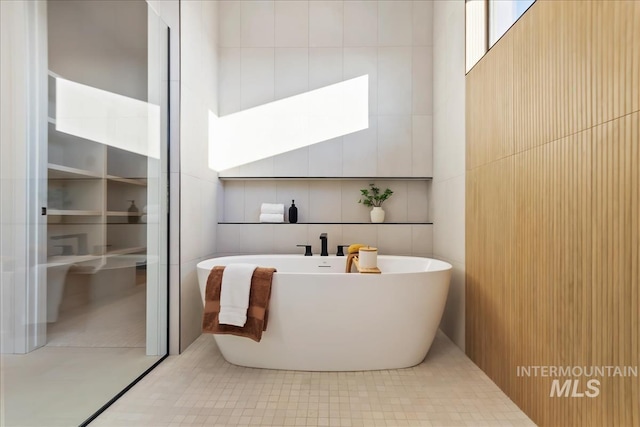 bathroom featuring tile patterned flooring, tile walls, and a tub