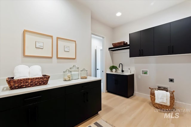 laundry area featuring cabinets, washer hookup, electric dryer hookup, sink, and light hardwood / wood-style flooring