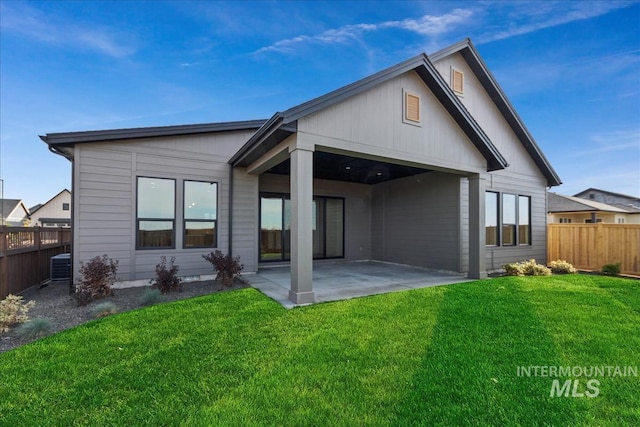 rear view of property featuring a patio, central AC, and a lawn