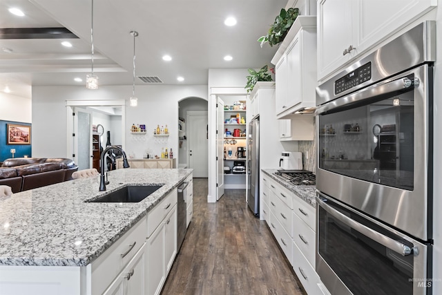 2133 N Star Garnet Ave, Kuna, ID 83634 - kitchen with a sink, open floor plan, arched walkways, white cabinetry, and dark wood-style flooring