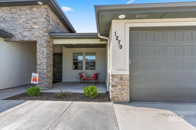 1279 W Ultar, Nampa, ID 83686 - entrance to property featuring an attached garage, stone siding, stucco siding, a porch, and concrete driveway