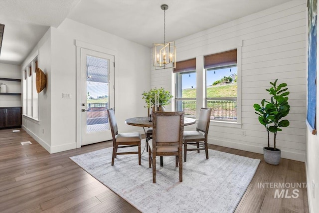 1279 W Ultar, Nampa, ID 83686 - dining room featuring baseboards, an inviting chandelier, wood walls, and wood finished floors